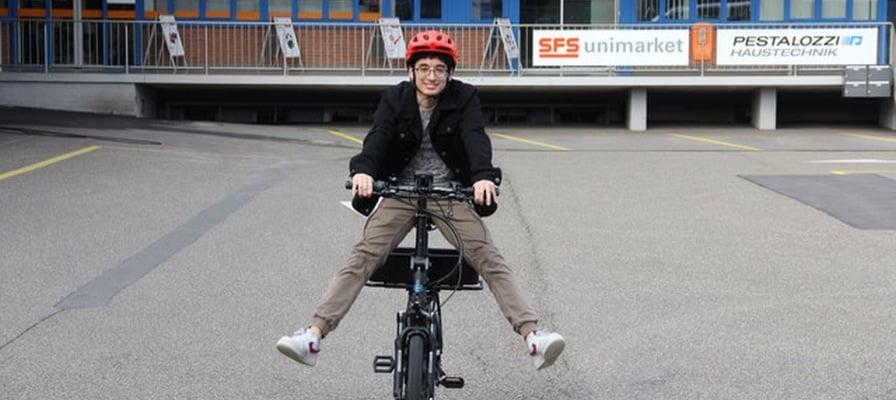 Mann auf E-Bike vor Pestalozzi-Gebäude mit rotem Helm