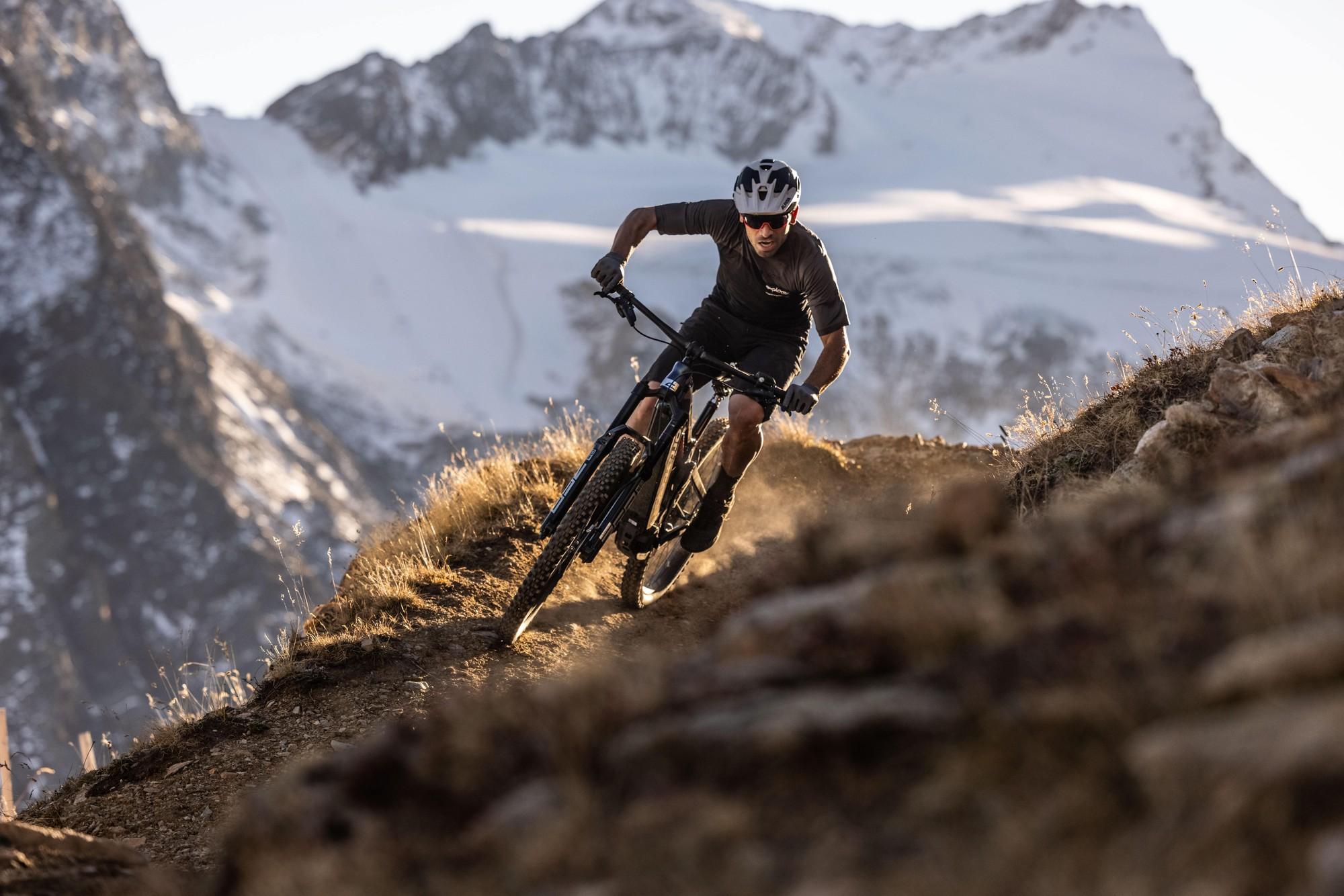 Fahrer, der auf einem E-Mountainbike der Marke Corratec eine steile, unebene Piste hinunterfährt.