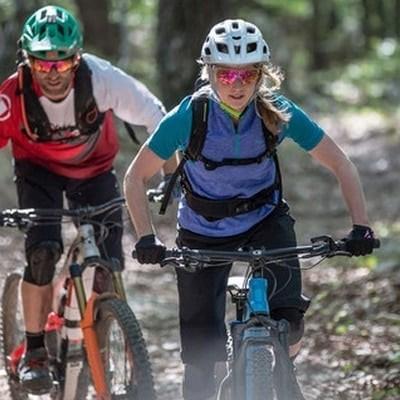 Zwei Mountainbiker auf Waldweg mit Schutzhelmen und Sportbekleidung