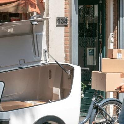 Person liefert Pakete mit Lastenrad in städtischer Umgebung