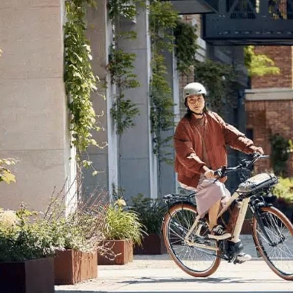 Person fährt E-Bike in urbaner Umgebung mit Helm