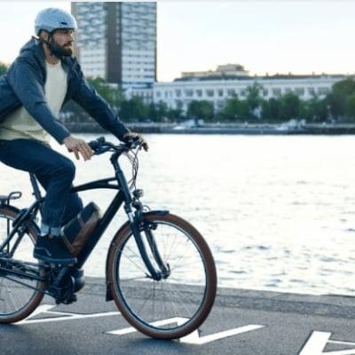 Mann auf E-Bike mit Fluss im Hintergrund bei Sonnenuntergang