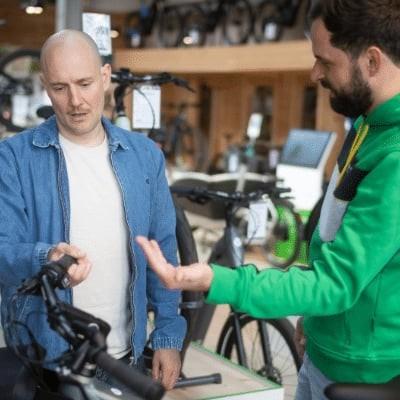 Zwei Männer diskutieren in einem Fahrradgeschäft vor E-Bikes