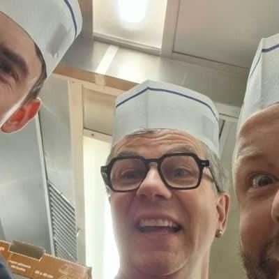 Drei Männer mit Papierhüten in einer Küche