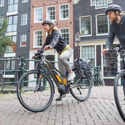 Zwei Personen fahren auf E-Bikes durch eine Stadtstraße