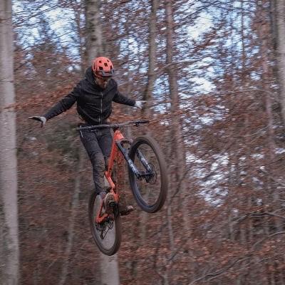 Mountainbiker springt mit Fahrrad durch herbstlichen Wald