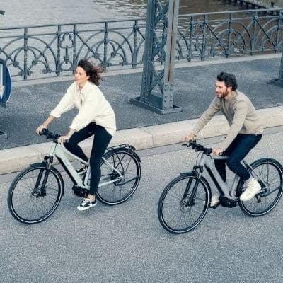 Zwei Personen fahren E-Bikes auf einer Brücke