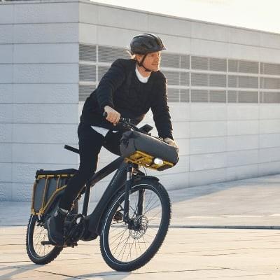 Mann fährt E-Bike auf urbanem Platz bei Sonnenuntergang