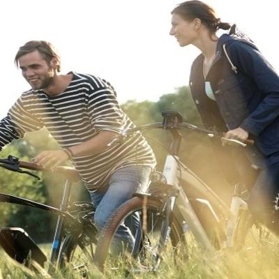 Zwei Personen auf E-Bikes bei sonnigem Ausflug durch die Natur