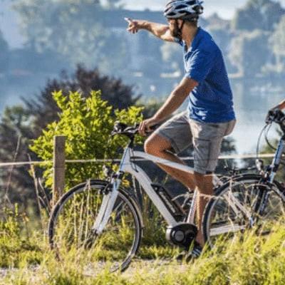 Zwei Personen fahren auf E-Bikes in der Natur mit Helmen