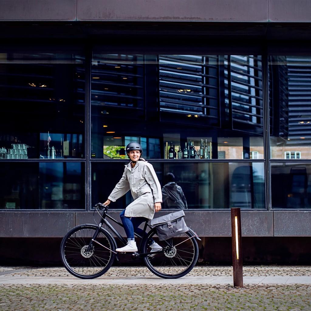 Eine Person fährt ein modernes E-Bike vor einem Stadtgebäude. Perfekt für urbane Mobilität und stilvolle Fortbewegu