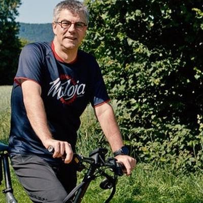 Mann auf einem Lasten-E-Bike vor einer grünen Landschaft