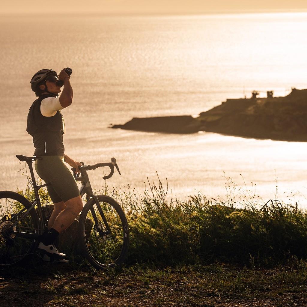 Fahrradfahrer steht mit seinem Grave-Bike am Meer, eine der komoot Routen von e-motion.