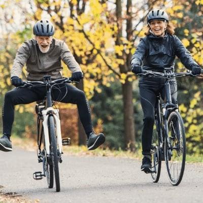Zwei Personen auf Fahrrädern im Herbstwald unterwegs