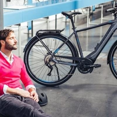 Mann entspannt sich neben E-Bike in modernem Innenraum