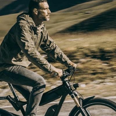 Mann fährt Riese & Müller E-Bike auf ländlicher Straße