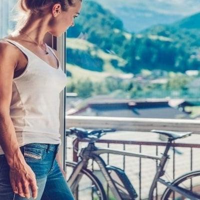 Frau betrachtet E-Bike auf Balkon mit Bergblick