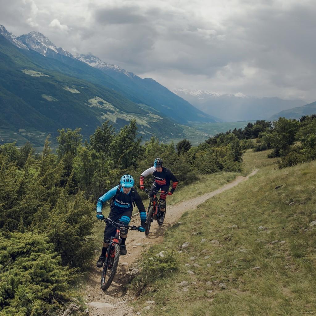 Zwei Radfahrer auf leistungsstarken E-Bikes erkunden einen malerischen Bergpfad. Erleben Sie Freiheit und Entdeckun