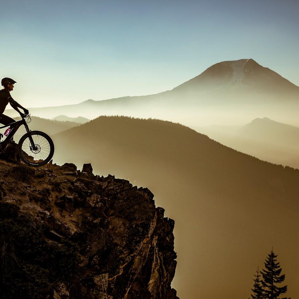 Ein Radfahrer auf einem E-Bike genießt die atemberaubende Aussicht von einem Berggipfel. Perfekt für Abenteuer und