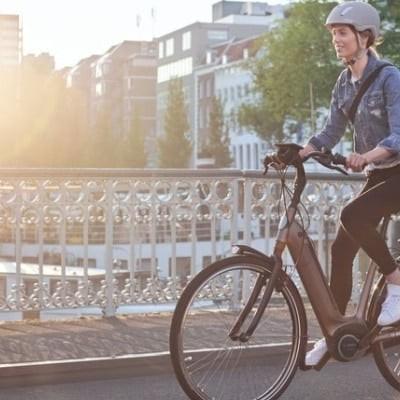 Frau auf Bosch E-Bike fährt über Brücke bei Sonnenuntergang