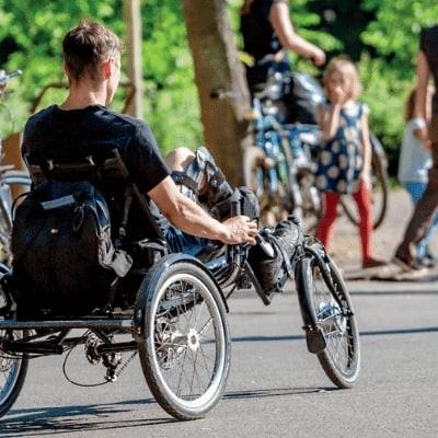 Menschen mit Fahrrädern und Liegedreirad im Park