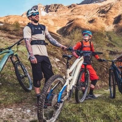 Gruppe von Mountainbikern auf einem Bergpfad mit Holzhütte im Hintergrund