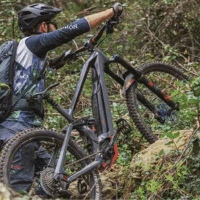 Mountainbiker trägt E-Bike mit Bosch CX Motor durch unwegsames Gelände