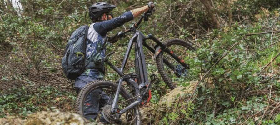 Mountainbiker trägt E-Bike mit Bosch CX Motor durch unwegsames Gelände