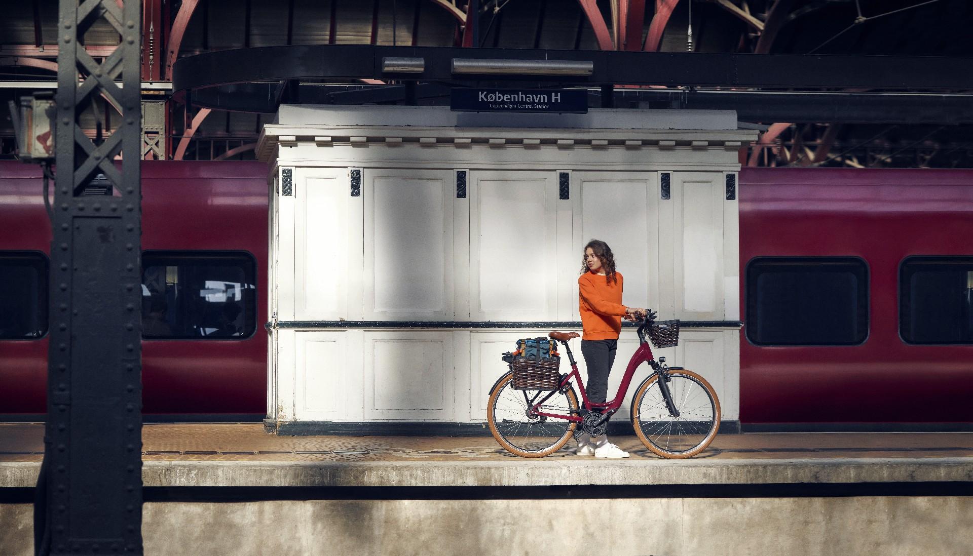 Eine Frau steht am Bahnsteig mit dem Riese & Müller Swing e-Bike