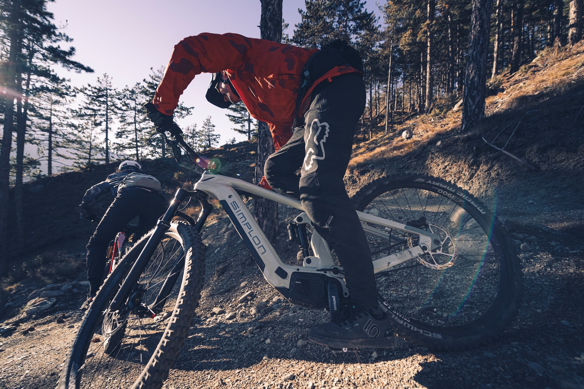 Zwei Radfahrer auf SIMPLON E-MTBs navigieren dynamisch durch einen Waldweg. Erleben Sie die Kraft und das Handling
