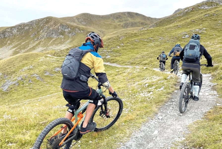 Mountainbiker auf schmalem Pfad in alpiner Landschaft