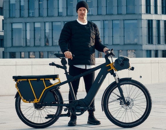 Mann mit schwarzem E-Bike vor modernem Gebäude