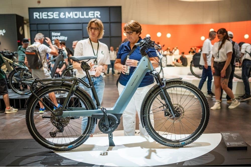 Riese & Müller E-Bike auf Messe mit Besuchern im Hintergrund
