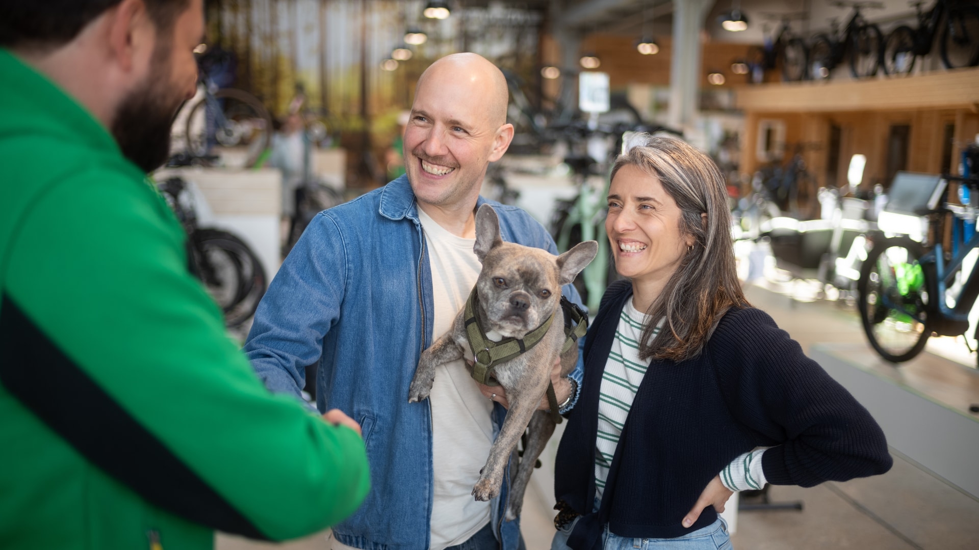 E-motion Mitarbeiter begrüßt Kunden mit Hund im E-Bike Shop. Entdecken Sie hochwertige E-Bikes für Ihre Abenteuer.