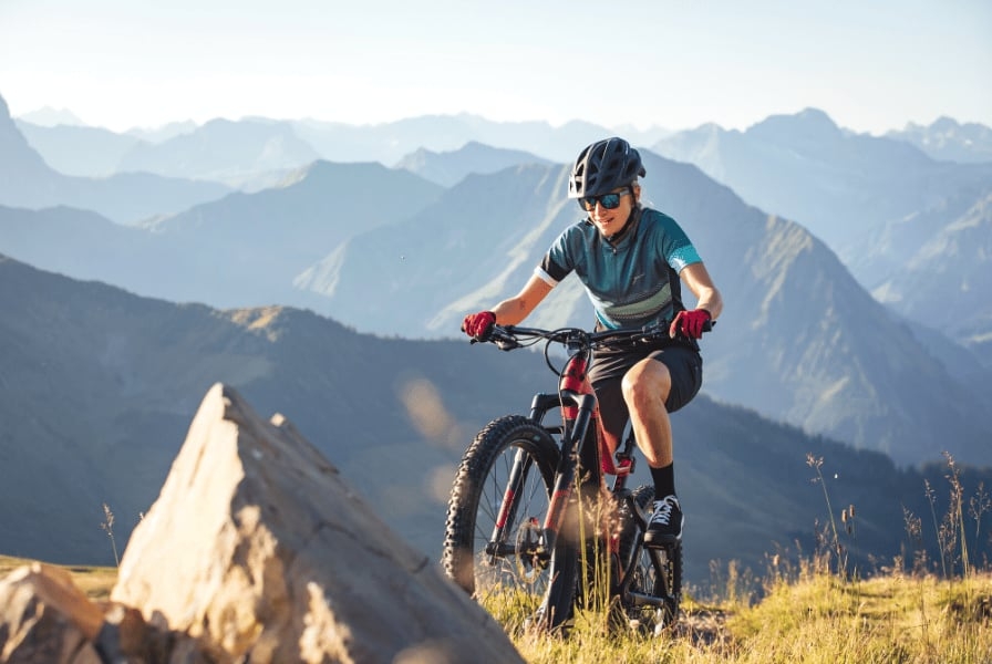 Mann auf E-Mountainbike in bergiger Landschaft bei Sonnenuntergang
