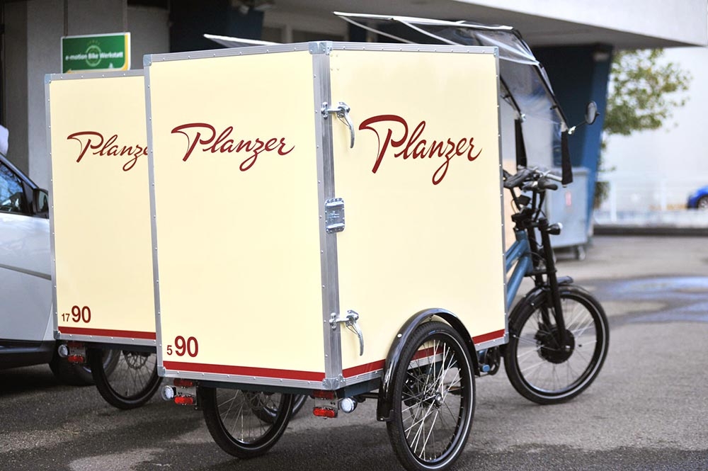 Das Bild zeigt ein Dreirad mit einer Transportbox von der Firma Planzer