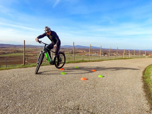 Ein Radfahrer navigiert einen Slalomkurs auf einer Landstraße, umgeben von malerischer Landschaft und klarer Himmel