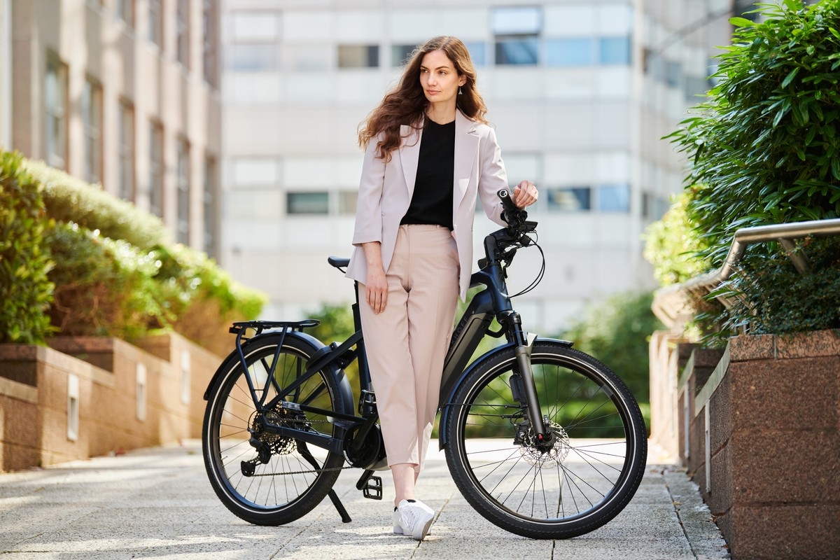 Das Bild zeigt eine junge Frau, die an einem modernen Kalkhoff York E-Bike steht.