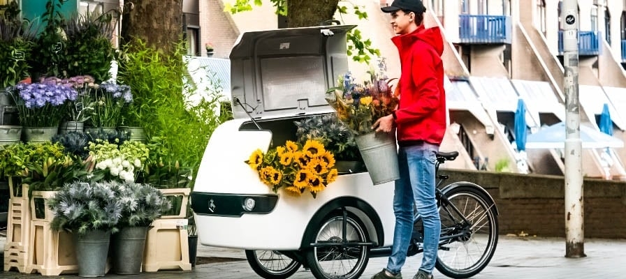 Mann mit Lastenrad transportiert Blumen in der Stadt