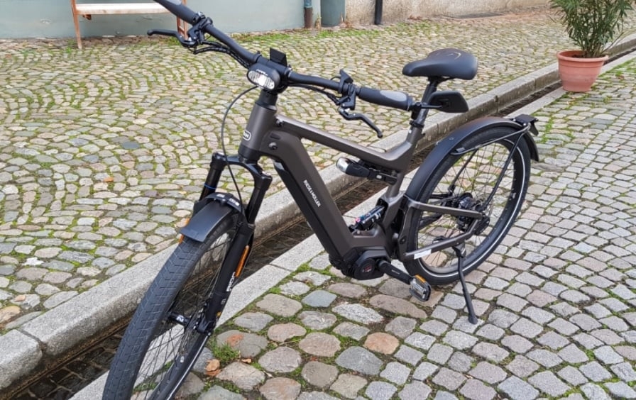 Graues E-Bike auf Kopfsteinpflaster mit Topfplanze im Hintergrund