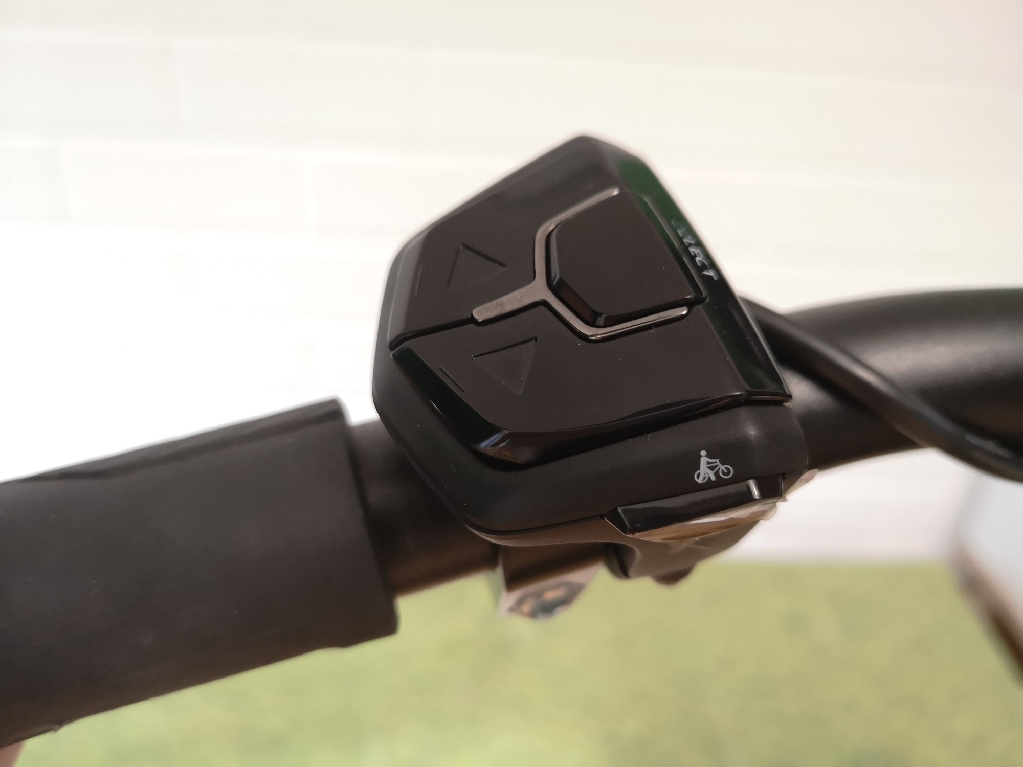 Schwarzes Bedienelement mit Pfeiltasten und Fahrradpiktogramm auf einem Fahrradlenker montiert. Ideal für E-Bike-St