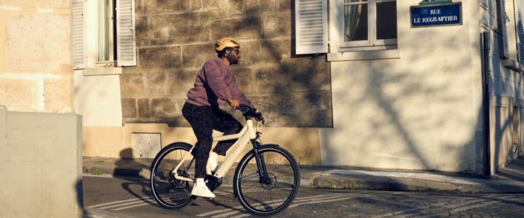 Mann mit Helm fährt E-Bike auf sonniger Stadtstraße