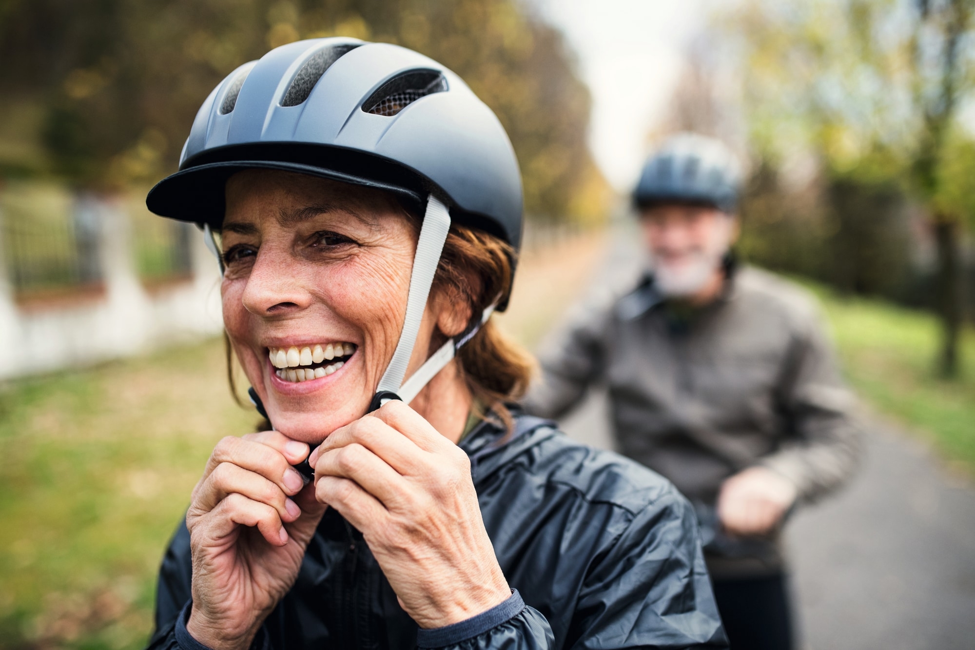 Eine lachende Frau stellt bei einer Fahrradtour ihren Helm ein. Genießen Sie Outdoor-Abenteuer mit sicherem Equipme