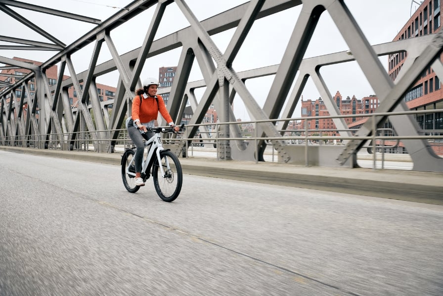Person auf einem KTM E-Bike fährt über eine Brücke in urbaner Umgebung