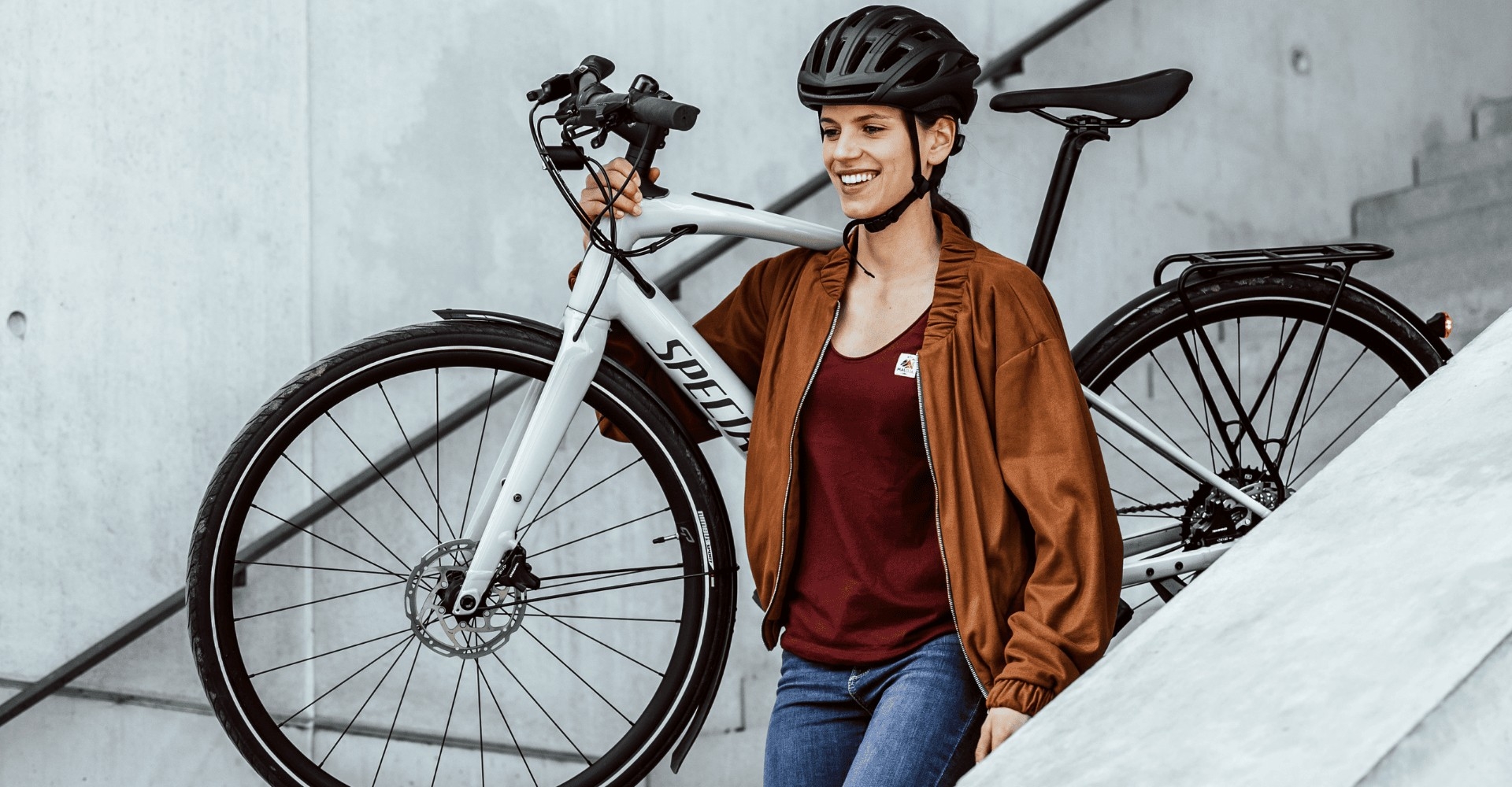 Eine Frau trägt das e-Bike Specialized Vado SL die Treppe runter