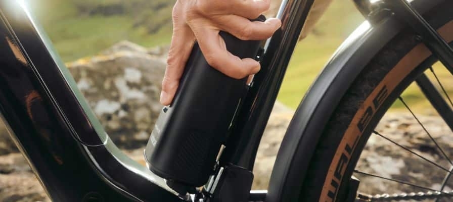 Hand montiert E-Bike-Akku an Fahrradrahmen in natürlicher Umgebung