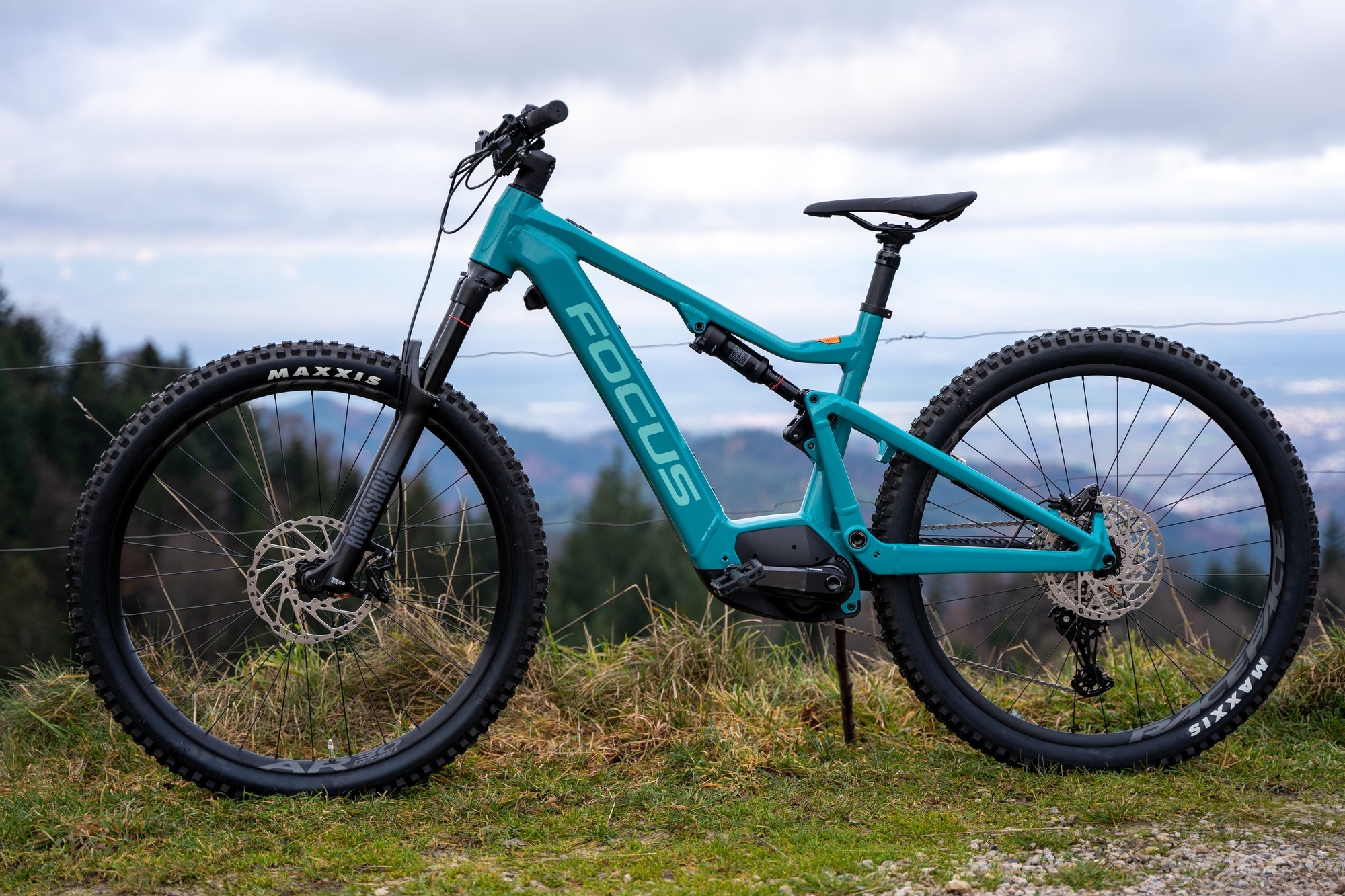 Das Bild zeigt ein Focus Jam² 7.8 E-Mountainbike, das in einer naturnahen Umgebung abgestellt ist.