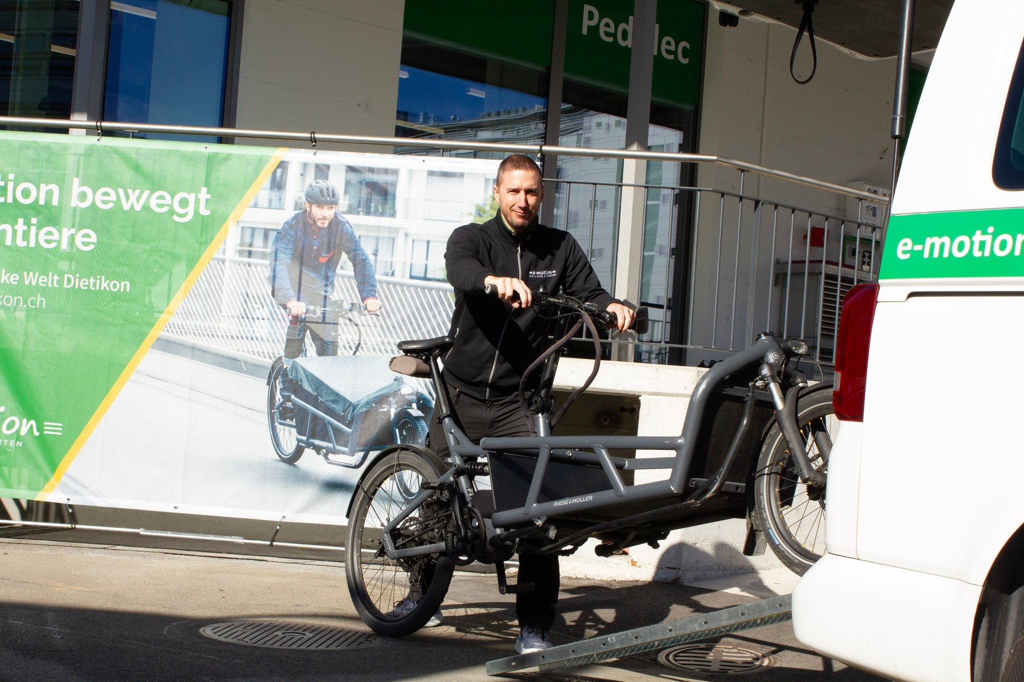 Das Bild zeigt einen Mitarbeiter des Hol- und Bringservices in Dietikon, der ein Cargo-E-Bike belädt.