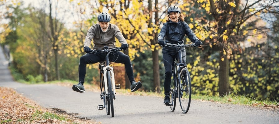 Zwei Personen auf Fahrrädern im Herbstwald unterwegs