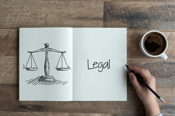 Skizze einer Waage und das Wort 'Legal' auf einem Notizblock